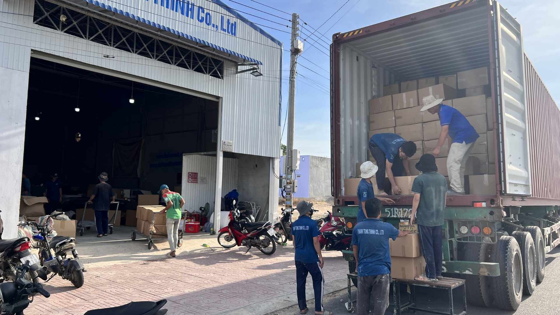 Workers loading wooden products onto a container for international export