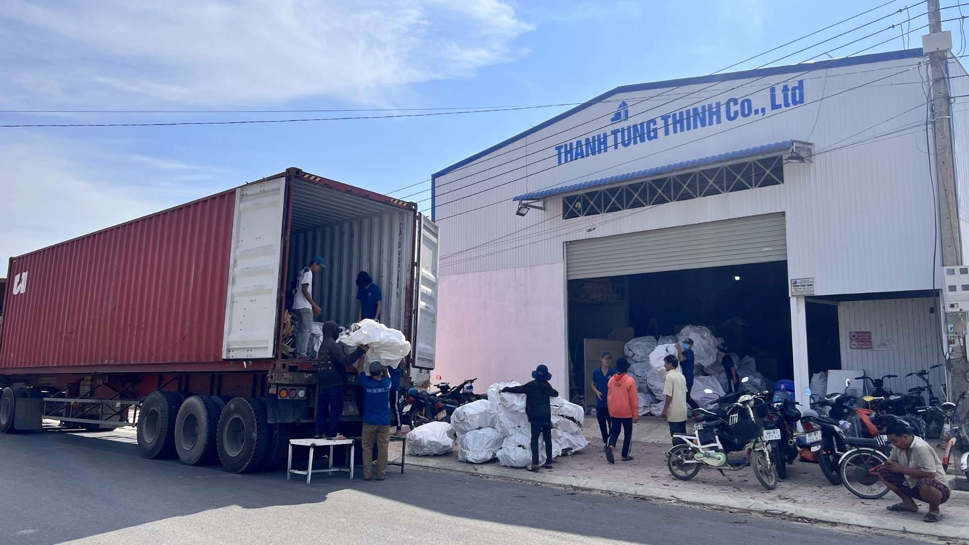 Workers loading wooden products onto a shipping container at the manufacturing facility for global export.