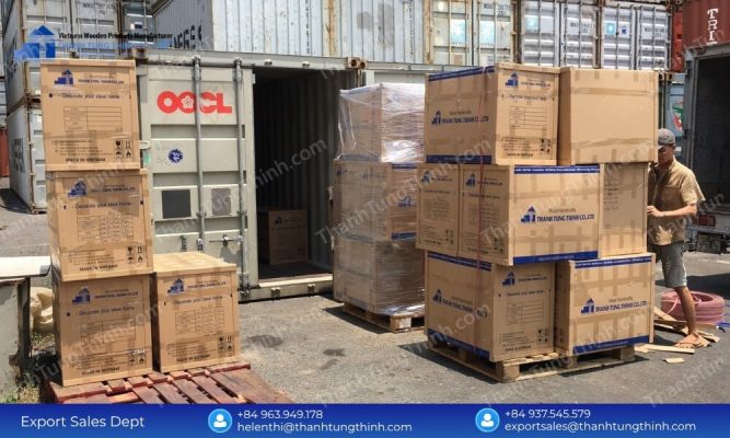 Factory staff arranging branded export cartons near an open shipping container for a bulk buy teak chopping boards order
