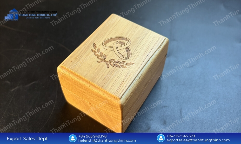 A small rectangular wooden box displaying a clean laser-engraved logo of intertwined wedding rings and olive leaves