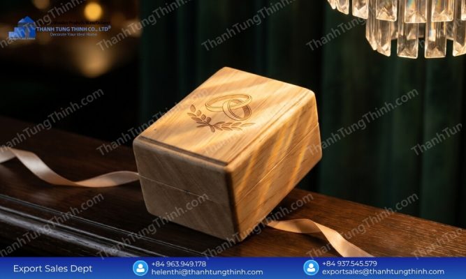 A premium laser-etched wooden ring box catching soft sunlight on a dark wooden countertop with a hanging crystal chandelier above