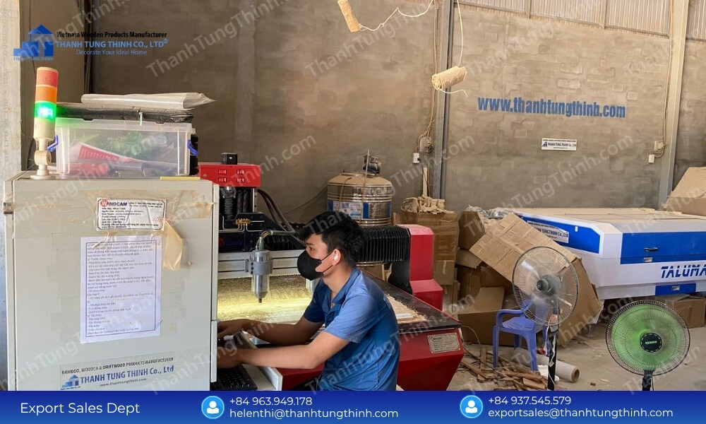 A factory worker operating an automated computer terminal connected to laser engraving machinery inside a large wood processing warehouse
