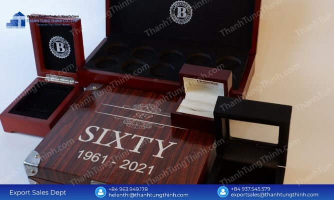 A collection of polished dark reddish-brown wooden boxes showcasing laser-engraved lettering and interior jewelry slots