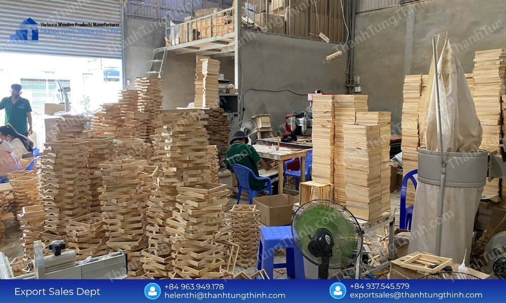 A warehouse interior showing massive columns of stacked square wood frames stretching toward the upper mezzanine level