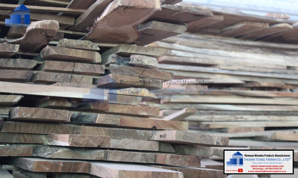 A large stack of raw commercial timber planks undergoing moisture stabilization inside a woodworking factory yard