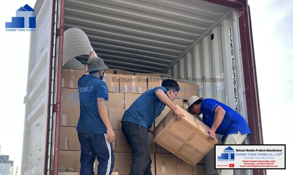 Factory shipping staff carefully loading heavy duty export corrugated cartons containing bulk kitchenware units into an ocean freight container